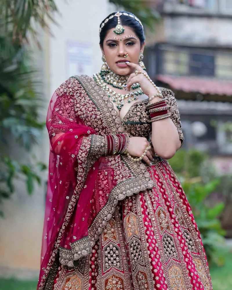Bridal portrait in a red and gold lehenga against a quiet street