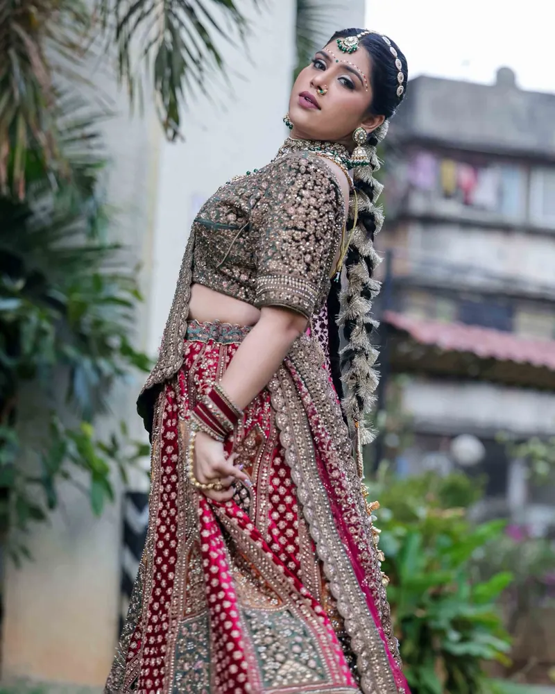 Bride turning to look over her shoulder in an embroidered lehenga outside an old building