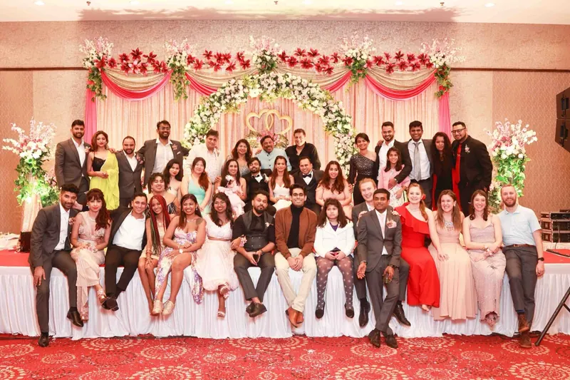 Large group of friends and family posing in front of a floral stage at an engagement party
