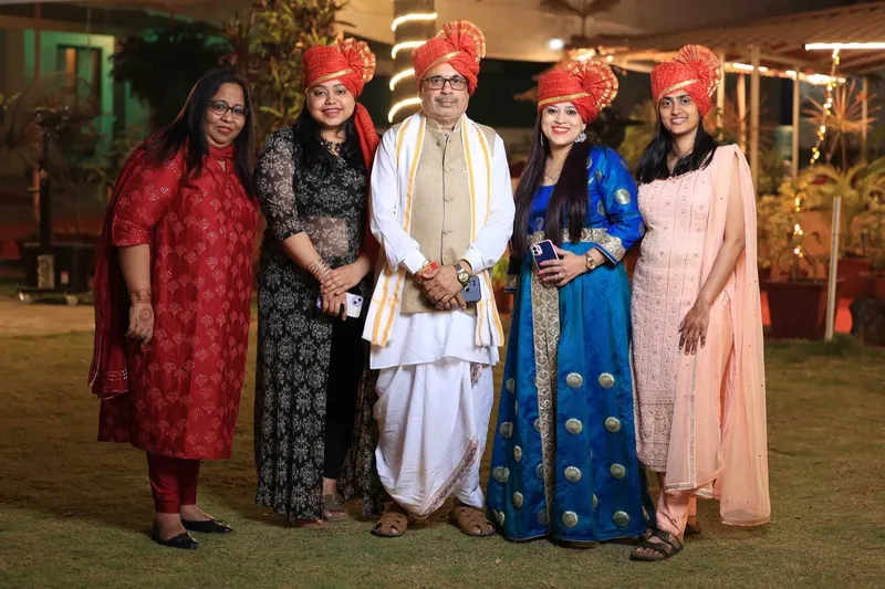 Family group in pink and orange pheta turbans posing together on a lawn at night